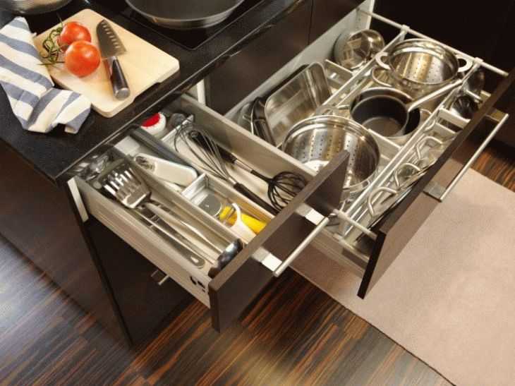 Хранить крышки или разделочные доски на кухне можно в разделителе для тарелок. Некоторые хозяйки к дну подвесного шкафчика крепят крючки, на которые за ручки вешают сковороды.